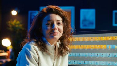 Mutlu fotoğraf editörünün portresi. Yaratıcı stüdyoda fotoğrafları düzeltiyor. Masanın yanındaki kahve fincanının yanında. Neşeli fotoğrafçı editoryal içerik için en iyi resimleri seçiyor, kamera A