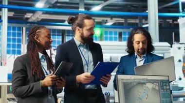 Fotovoltaik fabrikasındaki neşeli yöneticiler, güneş paneli üretiminin performansından memnunlar. Geçmekte olan güneş santrali makine denetimini kutlayan memnun yöneticiler, kamera B