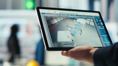 Fotovoltaik fabrikasındaki mühendis, güneş panelleri üreten robotların performansını gözden geçirmek için tablet üzerinde izleme yazılımı kullanıyor. Uzman, güneş santrali makinelerini incelemek için aygıt kullanır, kamera B.