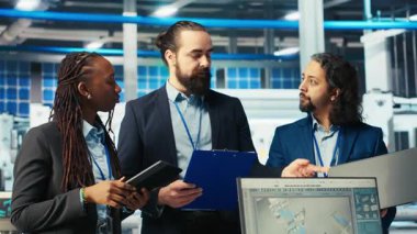 Fotovoltaik fabrikasındaki gülümseyen müfettişlerin portresi robot kolların performansını gözden geçiriyor güneş panellerini montaj hatlarına yerleştiriyor. Güneş santrali makinelerini inceleyen mutlu yöneticilerden oluşan bir ekip, kamera B