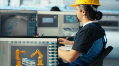 Fotovoltaik fabrikası mühendisi CAD yazılımı kullanıyor, tesis katında çalışma planlıyor. Güneş panelleri fabrika teknisyeni üretiyor. Bilgisayar, kamera B 'de montaj hatları dizayn ediyor.