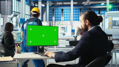 Fotovoltaik fabrika işçisi, güneş panelleri üreten robotların performansını izlemek için yeşil ekran bilgisayar kullanıyor. Uzman Chroma Key bilgisayar masasında oturuyor güneş santrali makinelerini inceliyor, kamera A