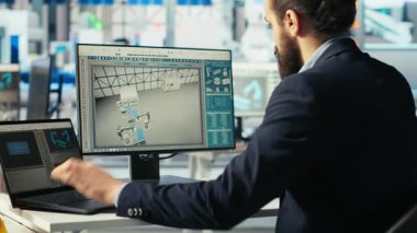 Fotovoltaik fabrikası teknisyeni sistem parametrelerini güneş pillerinin enerji üretimini maksimuma çıkarmak için dizüstü bilgisayara ayarlar. Güneş paneli imalat tesisinde enerji kaynağını optimize eden defter kullanan adam, kamera B