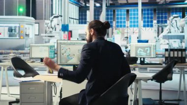 Uzman, güneş paneli montaj fotovoltaik fabrikası için üretim hatları tasarladıktan sonra masadan ayrılıyor, çalışmaya başlıyor. Teknisyen, fabrika üretim planlarından sonra çalışmaya hazır.