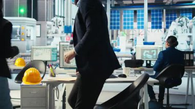 Fotovoltaik fabrikası yöneticisi güneş mühendisliği ekibiyle yeni sistem tasarımı ve güvenilirliğini geliştirmek için çalışıyor. Güneş paneli üretim tesisi müfettişi çalışanlara geri bildirim sağlıyor