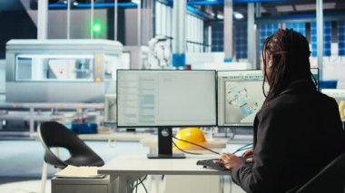 PC kullanarak fotovoltaik fabrikasındaki programcı robot kollarının güneş panellerini montaj hatlarına yerleştirdiği yazılımı güncelliyor. Bilgisayarda kodlama yapan kadın, güneş santrali makinelerini güncelleme, kamera A