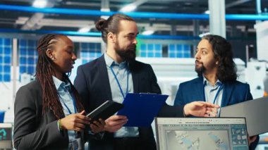 Fotovoltaik fabrikasındaki neşeli uzmanların portresi robot kolların performansını gözden geçiriyor güneş panellerini montaj hatlarına yerleştiriyor. Neşeli iş ortaklarından oluşan ekip güneş santrali makinelerini inceliyor