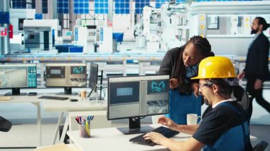 Fotovoltaik fabrika mühendisi CAD programında tesis ayarlaması yapıyor, kadını gösteriyor. Güneş panelleri fabrika teknisyeni montaj hatları dizayn ediyor, Afrikalı Amerikalı yöneticiyi bilgilendiriyor, kamera A