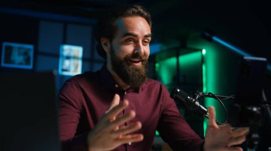 ASMR sanatçısı stüdyoda tripodun üzerinde kaliteli mikrofon ve akıllı telefon kullanarak stres önleyici videolar çekiyor, fısıltı sesleri çıkarıyor. Adam uyumak için mikrofon ve cep telefonu kullanıyor. İçeriği tetikliyor, kamera B