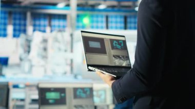 Güneş panelleri enerji sistemlerini incelemek için dizüstü bilgisayar kullanarak güneş enerjisini kullanan yeni teknolojiler geliştiriyor. Fotovoltaik fabrikası araştırmacısı verimliliği arttırmak için defter üzerinde çalışıyor, kamera B