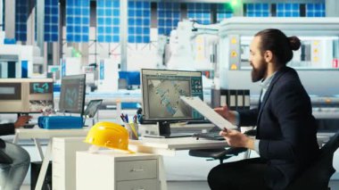 Fotovoltaik fabrikası müdürü evrak işlerine bakıyor, sistem performansını izliyor. Güneş panelleri imalat tesisi yöneticisi belgelere bakıyor, enerji üretimini izliyor