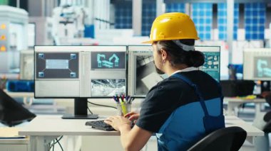 Robot kollarını test etmek için bilgisayar kullanan fotovoltaik fabrikası mühendisi güneş panellerini montaj hatlarına yerleştiriyor. Profesyonel olarak bilgisayar masasında oturup güneş santrali ağır makine ünitelerini, kamera B 'yi inceliyorum.