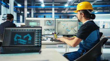 Fotovoltaik fabrikasındaki mühendis sarı başlık takıyor. Arızalı sistemleri tespit etmek için bilgisayar kullanıyor. Güneş panelleri fabrika işçisi üretiyor ağır makine birimlerini azaltıyor, kamera A