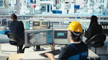 Fotovoltaik fabrikası mühendisi CAD yazılımı kullanıyor, tesis katında çalışma planlıyor. Güneş panelleri fabrika teknisyeni üretiyor bilgisayar ve kamera A 'da montaj hatları dizayn ediyor.