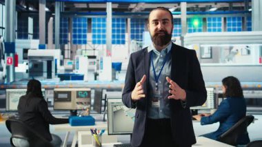 Güneş paneli fabrikasındaki adam konuşuyor, yenilenebilir enerji üretimi hakkında bilgilendirme videosu çekiyor. Fotovoltaik fabrikası uzmanı video kaydı, güneş paneli üretim sürecini açıklıyor, kamera A