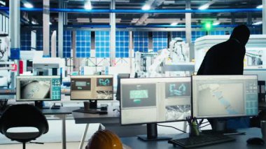 Fotovoltaik fabrikasındaki maskeli işçi şirket casusluğu yapıyor, USB çubuğu kullanarak tescilli teknolojiyi çalıyor. İnsan, güneş paneli fabrikasından ve kamera A 'dan gelen ticari sırlara içeriden erişimi sömürüyor.