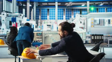 Photovoltaics fabrika müdürü robot silahlarının performans raporlarını inceledi güneş panellerini montaj hatlarına yerleştirdi. Denetmen, güneş santrali makine parametrelerinin denetim veri dosyalarını okuyor