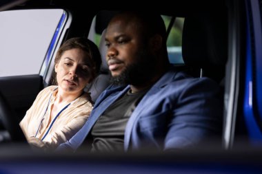 Araba galerisi satıcısı. Sürücünün yanında. Araç yeteneklerini göstermek için test sürüşü yapıyor. Galeride çalışan bir kadın, araba kullanırken erkeklerin alması için isteğe bağlı ekipman öneriyor.