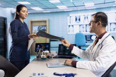 Profesyonel doktor ve hasta röntgen ve MRI sonuçlarının taranması için tıbbi konsültasyona girer. Sağlık uygulamaları ve tıbbi araştırmaları vurgulayan pratisyen hekim.