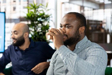 Girişimci şirkette bir fincan kahvenin tadını çıkaran, mali iş belgelerine bakan bir adam. Ofisteki işçiler enerji kazanmak için kafeinli içecekler içip sıkıcı evrak işlerini bitirmeye çalışıyorlar.