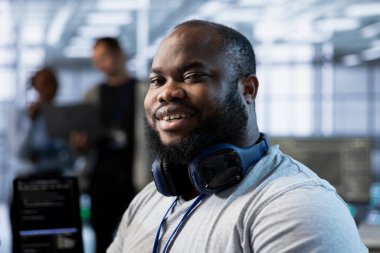 Sunucu odasındaki gülümseyen mühendisin portresi enerji tüketimini azaltmak için güç yönetimi çözümleri uyguluyor. Veri merkezinde yeni teknolojileri birleştiren mutlu bilişim uzmanı, kapat