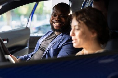 Neşeli insanlar test sürüşünü bitiriyor, araba galerisi satıcısıyla anlaştıktan sonra tatmin oluyorlar. Gülümseyen Afro-Amerikan bir adam galeride araba kullandıktan sonra alışveriş yapmaya karar veriyor.