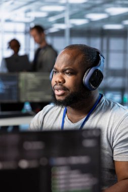 Veri merkezinde mühendis müzik dinliyor, ağ yönetimi becerilerini kullanarak bilişim altyapısını optimize ediyor. Sunucu odası uzmanı kulaklık takıyor, vites yükseltiyor, işletme maliyetlerini düşürüyor