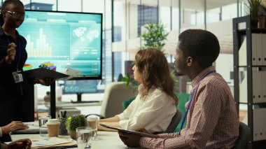 Çeşitli profesyonel gruplar yeni bir geliştirme stratejisini tartışmak için toplanıyor, bilgi grafikleri ve aylık analiz numaralarını kullanarak hedefe ulaşıyor ve örgütsel hedeflere ulaşılıyor. Kamera B.