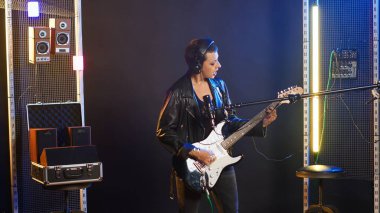 Deri ceketli, heavy metal çalan rock yıldızı kadın elektro gitarını enerjiyle parçalıyor. Grunge stili cesur asi müzisyen onun ikonik canlı performansını tanımlıyor. Kamera B.