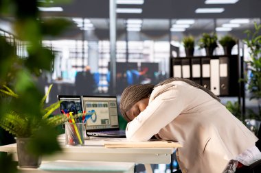 Yorgun yönetici veri ölçümlerini analiz ederek şirketin performansını değerlendirirken bilgisayar masasında uyuyakalıyor. Yorgun iş kadını idari operasyonları denetlerken uyukluyor