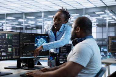 Mühendis, veri merkezindeki farklı iş yükleri için kaynak sağlayan görevlerin nasıl bitirileceğini gösteriyor. Ekip lideri IT uzmanına süper bilgisayarları izlemeyi öğretiyor, ekranı işaret ediyor