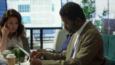 Tablet üzerindeki bilgi grafikleri ve kaynak tahsisini inceleyen hissedar, strateji oturumu için ortaklarla bir araya geliyor. Gelişme için yenilikçi çözümler geliştirmek için veri analizleri kullanılıyor. Kamera A.