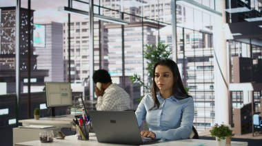 Hintli iş kadını ofis masasındaki bilgisayarında iş tahminleri ve planlarını gözden geçiriyor, strateji planlaması yapıyor. Veri analisti şirketin amaçlarına ve kaynak tahsisine odaklanıyor. Kamera B.