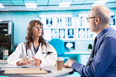 Pratisyen hekimlerin erkek hastalara danışmaları ve test sonuçlarını incelemeleri, bir klinikte hasta bakımı ve analizi için yüksek teknoloji araçları kullanmaları. Sağlık hizmeti sağlayıcısı.