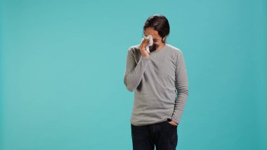 Portrait of troubled man weeping feeling saddened and rattled by events, isolated over studio backdrop. Person crying, wiping tears with handkerchief, left speechless by troubling news, camera A clipart