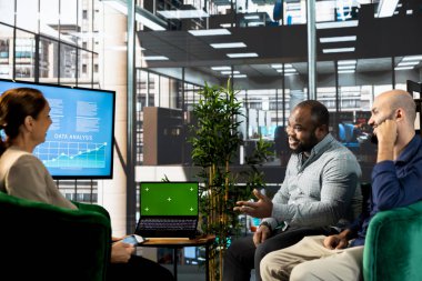 Çok ırklı takım tarafından iş toplantısına hazırlanan, tartışan yeşil ekran dizüstü bilgisayar. Başlangıçta beyin fırtınası yapan çok ırklı çalışanların kullandığı bir defter.