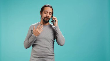 Arkadaşlarıyla telefon görüşmesinde konuşan gülümseyen bir adamın portresi. Akıllı telefon, stüdyo geçmişi. Neşeli insan telefon görüşmesi sırasında iyi haberler aldıktan sonra pozitif hissediyor, kamera B