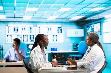 Afrika kökenli Amerikalı bir hasta tıbbi bir muayenehanede bir doktorla görüşüyor, kişisel bakım veya tedavi için teşhis raporlarını ve analizleri tartışıyor. Sağlık için tavsiye sunuyor..