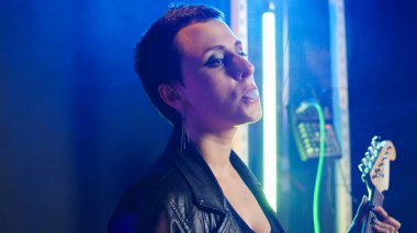 Gece kulübünde sakız çiğneyen kadın rock yıldızı cesur bir tavırla havalı ve isyankar davranıyor. Kadın müzisyen, heavy metal yapıyor. Kapatın. Kamera A.