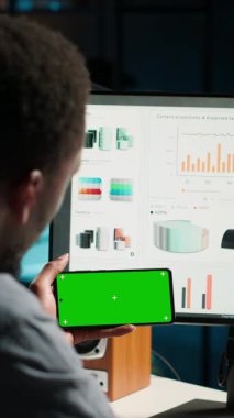 Dikey Video Genç kişi, veri finansmanını yeşil ekranla kullanarak, çalışma yerindeki istatistikleri inceleyerek uzaktan çalışma yapıyor. Yatırım danışmanı kalkınma için fon elde etmek için yeni bir strateji planlıyor