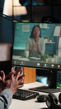 Dikey Video Genç Siyah Adam bilgisayarında meslektaşlarıyla bir video görüşmesi yapıyor, uzak bir konferansa katılıyor ve ev ofisinden giyiniyor. Freelancer telekonferansı. Kamera.