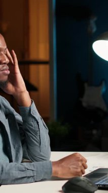 Dikey video geliştiricisi yorgun hissediyor ve görev teslim tarihine yetişmeye çalışıyor. Raporu zamanında bitirmek ve baş ağrısıyla başa kalmak için çok çalışıyor. Afrika kökenli Amerikalı adam stres altında.