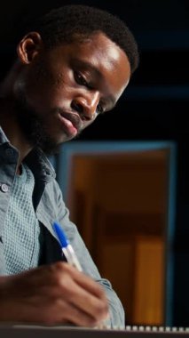 Dikey video odaklı kendi kendine çalışan yetişkin araştırmaları evdeki veri odaklı konular, el yazısı notlar yazmak ve uzaktan çalışma ortamında görevleri çözmek. Şık bir daireden projeleri yönetmek