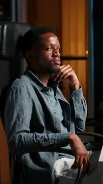 Dikey Video Siyah genç yetişkin uzaktan çalışıyor ve bilgileri düzenliyor, notları gözden geçiriyor ve serbest görevlerini tamamlamak için veri güdümlü kararlar alıyor. Programını etkili bir şekilde yönetiyor.