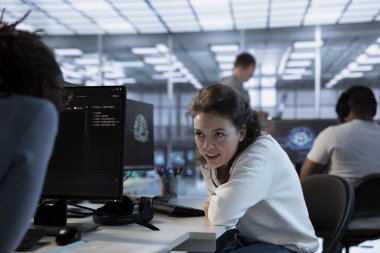 Yapay zeka sinir ağlarının bakımını yaparken iş arkadaşıyla sohbet eden neşeli bir teknisyen. Yapay zeka sistemlerini işleme yardım etmek için kullanırken, gülümseyen yönetici iş arkadaşıyla konuşuyor