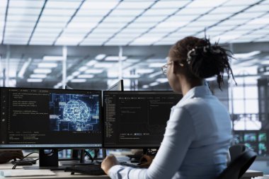 Bilgisayar masasında çalışan bir mühendis, AI sunucu odasında bilgisayar kaynakları sağlıyor. Bilgisayar kullanarak veri merkezlerini araştıran Afrikalı Amerikalı bilişim uzmanı.