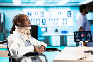 Tekerlekli sandalyedeki bir kız doktorla boyun yaralanması hakkında sağlık kontrolüne katılıyor. İyileşme sürecinde yardım öneriyor. Fiziksel engelli bir hasta tıbbi tasma takıyor..