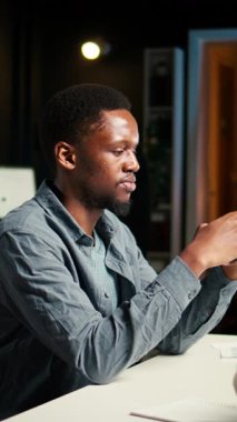 Evden çalışan ve cep telefonunu kullanan, sosyal medyada gezinen ve günlük görevlerini tamamlamadan önce e-postalarına cevap veren dikey video Independent yetişkin telgrafı. Konforlu modern kurulum