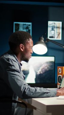 Dikey Video Siyah genç yetişkin uzaktan çalışıyor ve bilgileri düzenliyor, notları gözden geçiriyor ve serbest görevlerini tamamlamak için veri güdümlü kararlar alıyor. Programını etkili bir şekilde yönetiyor.