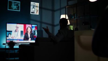 Akıllı TV 'de haber başlıklarını okuyan meraklı izleyiciler, koltukta oturup gazetecilerin son zamanlardaki küresel olaylarını dinliyorlar. Günlük haber başlıklarını izleyen adam, televizyon içeriği. Kamera A.